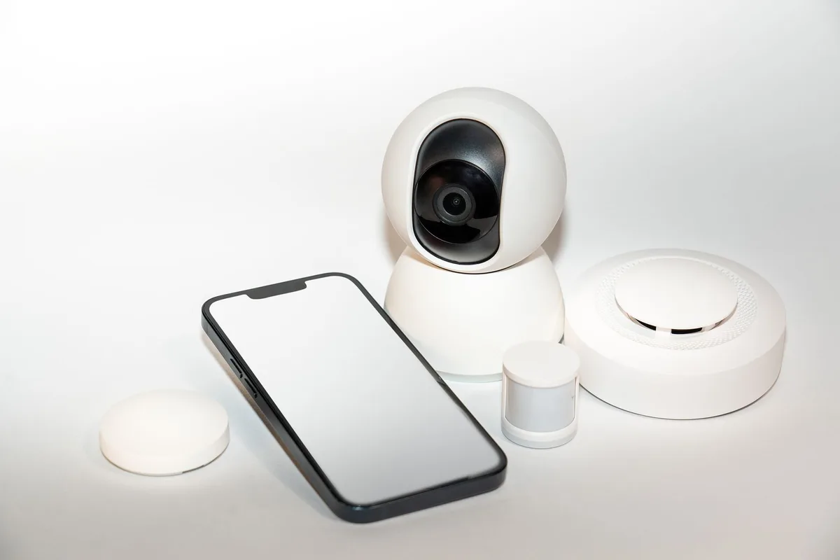 A modern smart home hub display with a 7-inch square screen showing personalized interface elements, integrated camera lens visible at the top, minimalist design