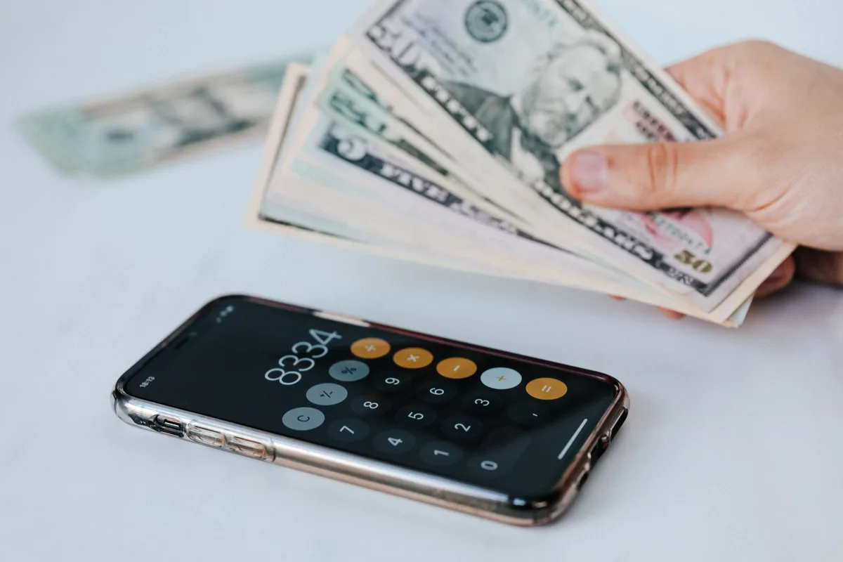 A smartphone displaying a split bill calculation with multiple users' names and amounts, modern minimalist design