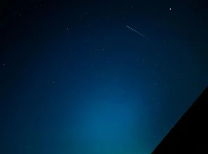Asteroide brillante acercándose en el cielo nocturno estrellado sobre un paisaje silhuetado