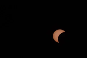Observador mirando al cielo durante un eclipse solar con nubes dispersas