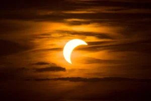 Multitud de personas observando un eclipse con gafas especiales, siluetas contra el cielo oscurecido