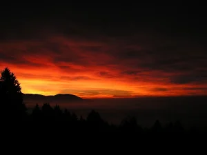 Observador en silueta mirando hacia el horizonte occidental al atardecer, con nubes dispersas sobre el cielo