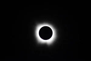 Oscuridad durante un eclipse solar total con la corona solar visible alrededor de la Luna
