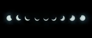 Cámara con filtro solar apuntando al cielo durante un eclipse, con personas observando en la distancia