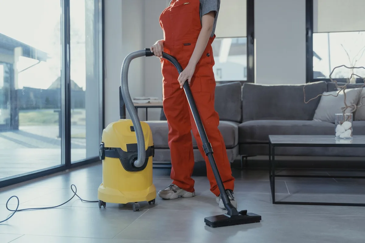 A professional steam cleaner being used on grout lines between white tiles, with steam rising and moisture visible, showing the deep-cleaning action on tile joints.