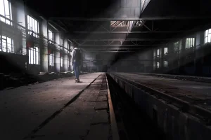 Túnel subterráneo oscuro con luz ultravioleta parpadeante iluminando objetos dispersos y siluetas en la distancia.
