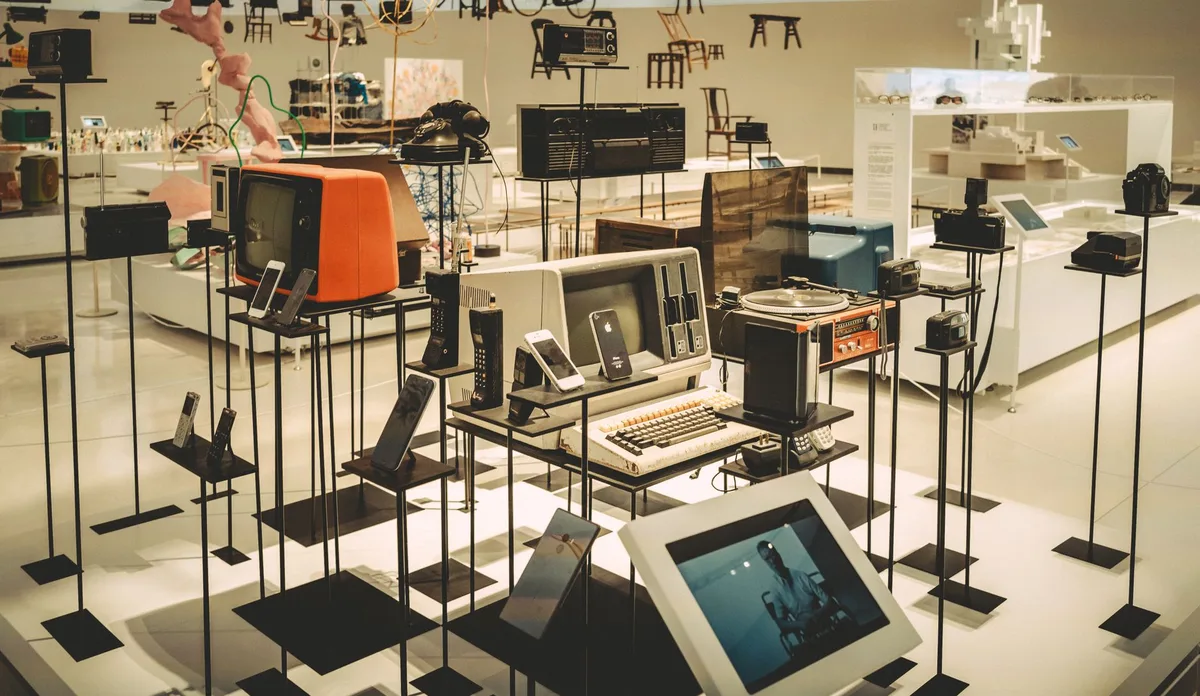 Rows of computer monitors and televisions displayed in a tech store, price tags visible, warm lighting emphasizing affordability