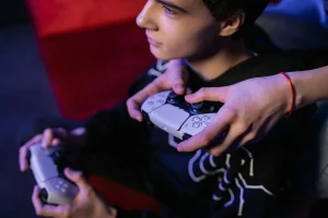 Jugador con controlador en mano frente a pantalla iluminada en ambiente oscuro