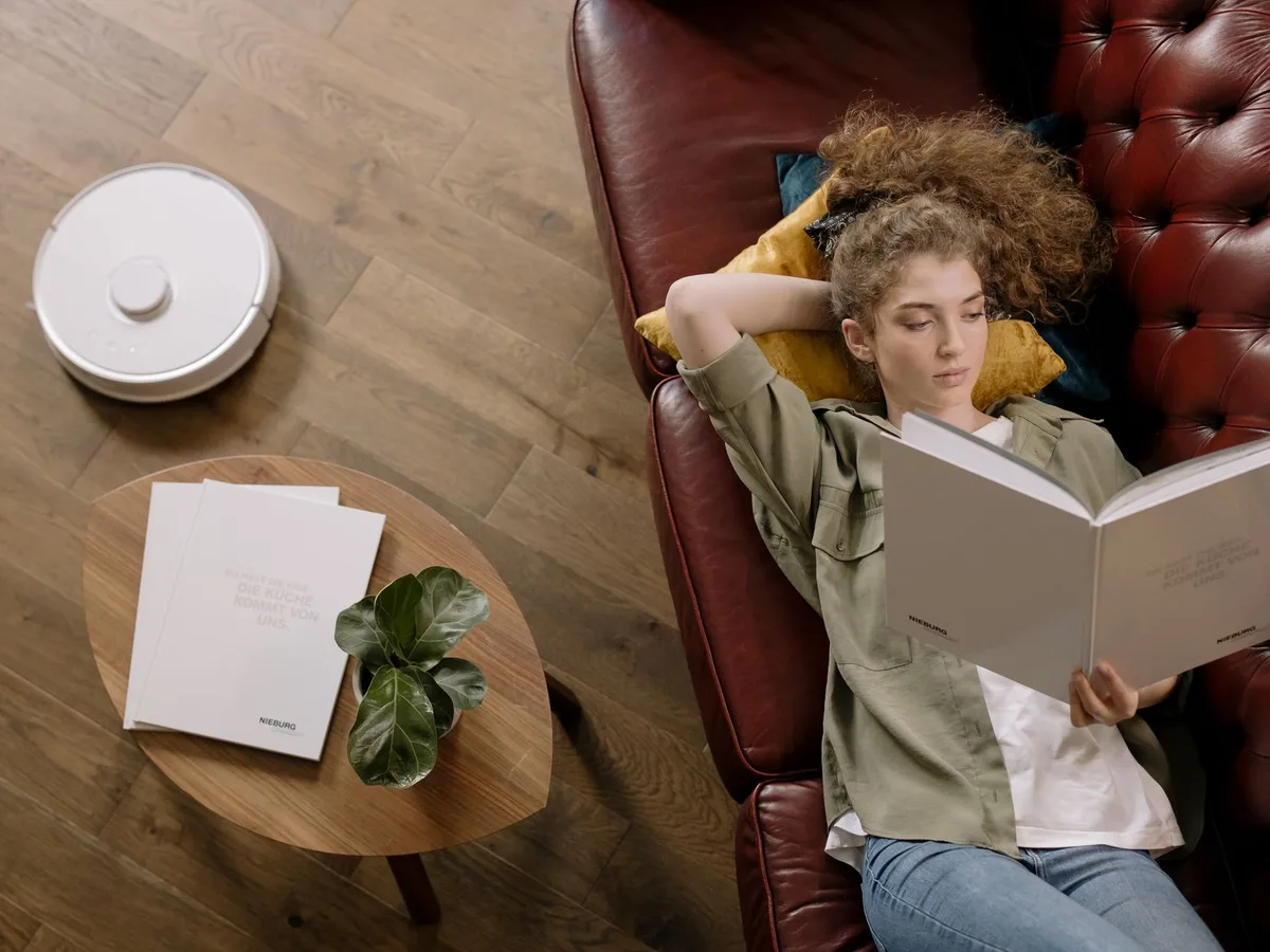 A retractable sensor mechanism on a compact robot vacuum beneath low furniture, showing the innovation in height reduction