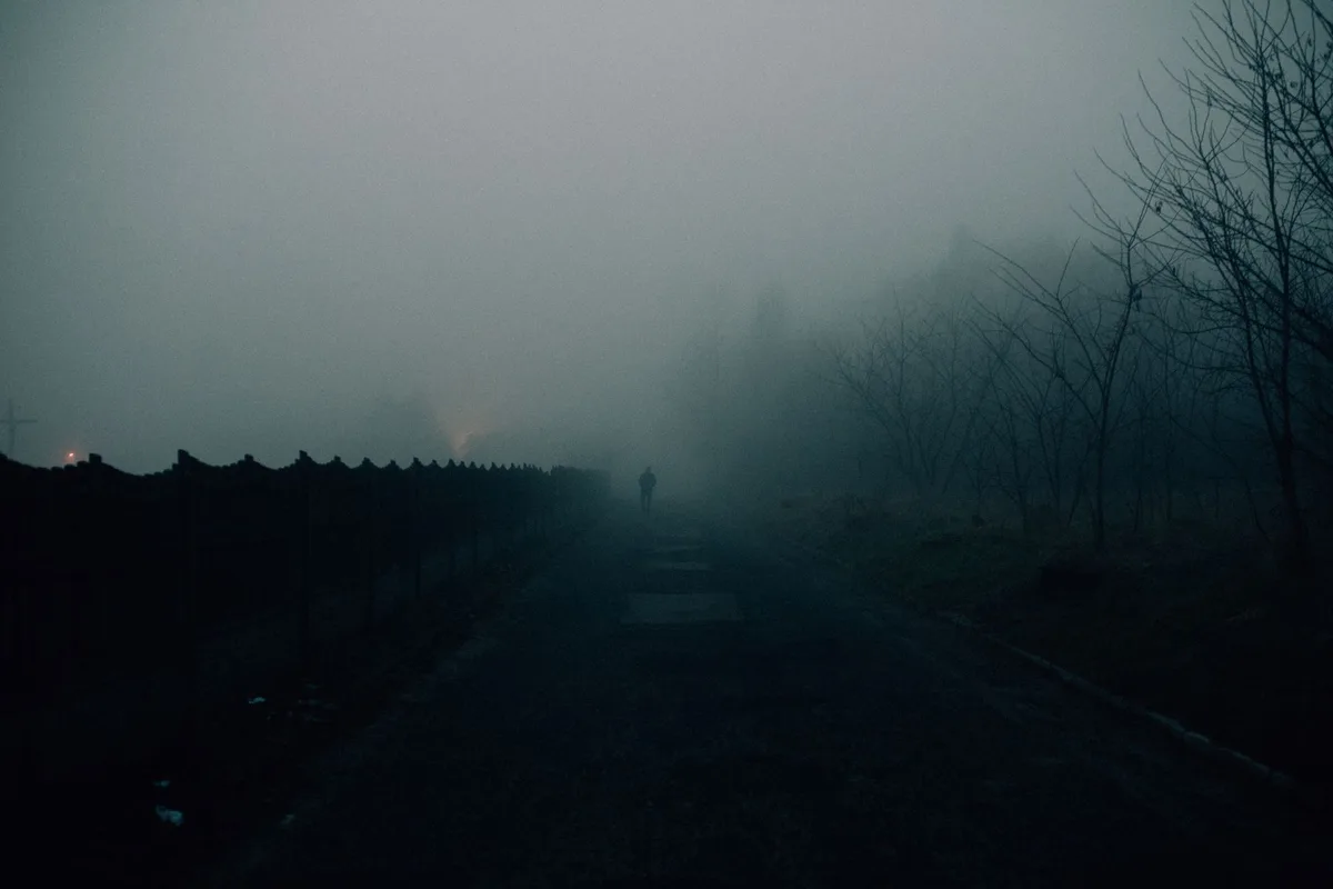 Pueblo aislado envuelto en niebla con atmósfera misteriosa y claustrofóbica