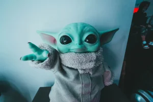 Peluche de oso rodeado de iconos digitales de compras, cine, música y videojuegos en fondo urbano