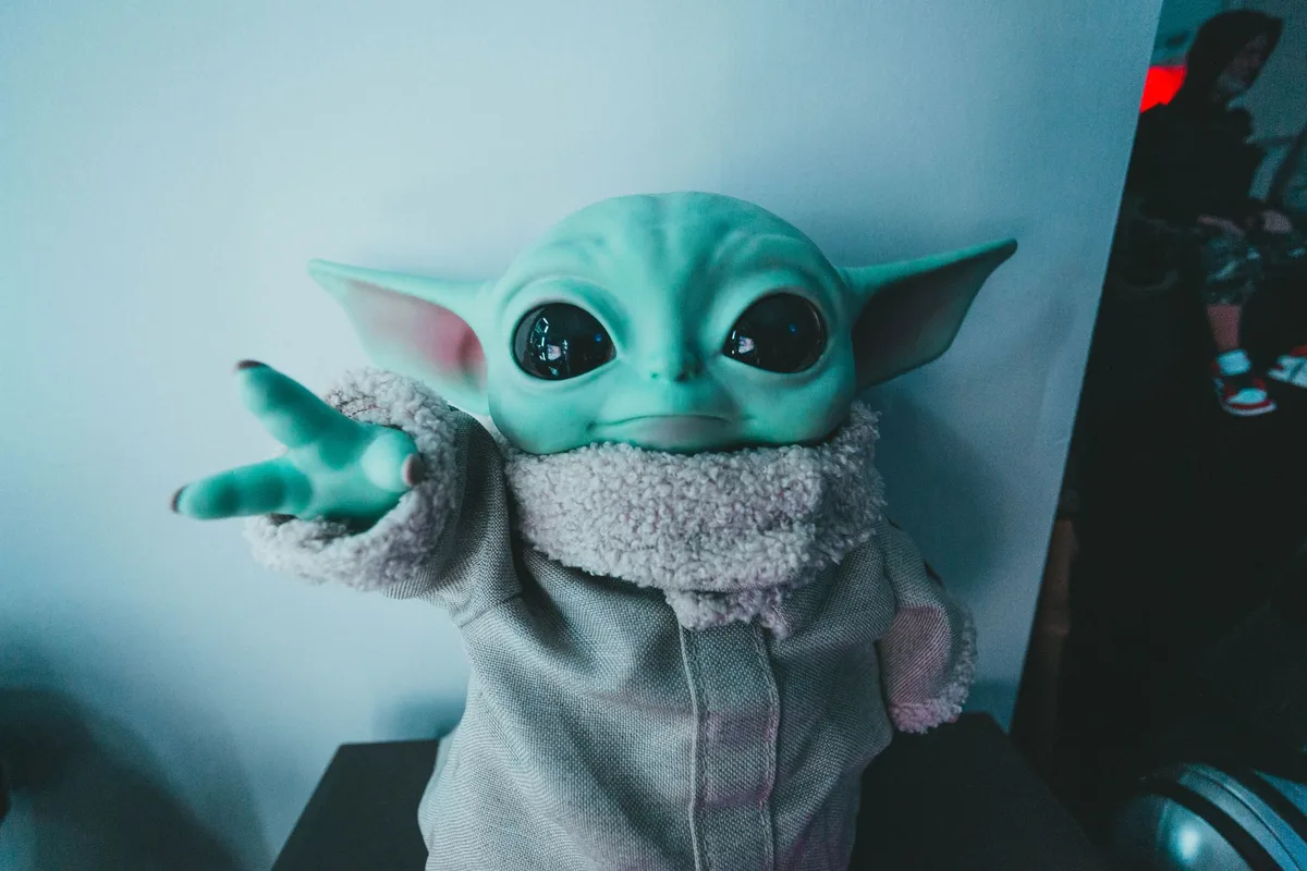 Peluche de oso rodeado de iconos digitales de compras, cine, música y videojuegos en fondo urbano