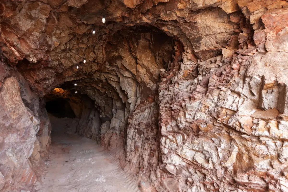 Túnel de mina abandonado con luces tenues y sombras oscuras