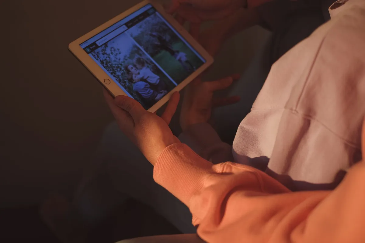A hand holding a tablet displaying a vibrant 2.5K resolution image of a landscape, with the device's aluminum frame catching soft light, showing the premium build quality