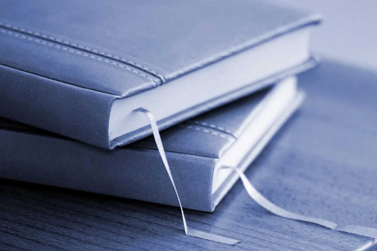 Close-up of a generic locked folder icon on a neutral background next to an anonymous printed contract and a pen, representing data protection and redaction