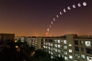 Grupo de personas en silueta mirando la Luna parcialmente eclipsada sobre el horizonte occidental
