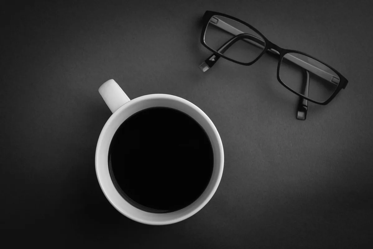 Persona trabajando en escritorio con pantalla de código y datos, iluminada por luz de ordenador en oficina moderna