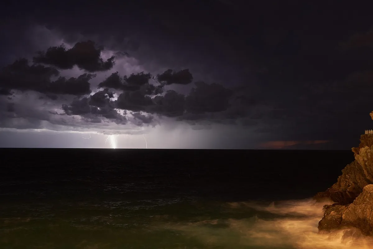 Tormenta eléctrica sobre laderas montañosas con bosque trasero
