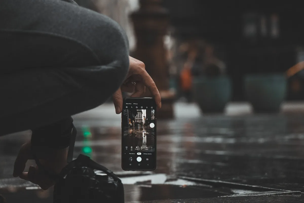 Manos sosteniendo un teléfono inteligente mientras graba vídeo de un sujeto en movimiento