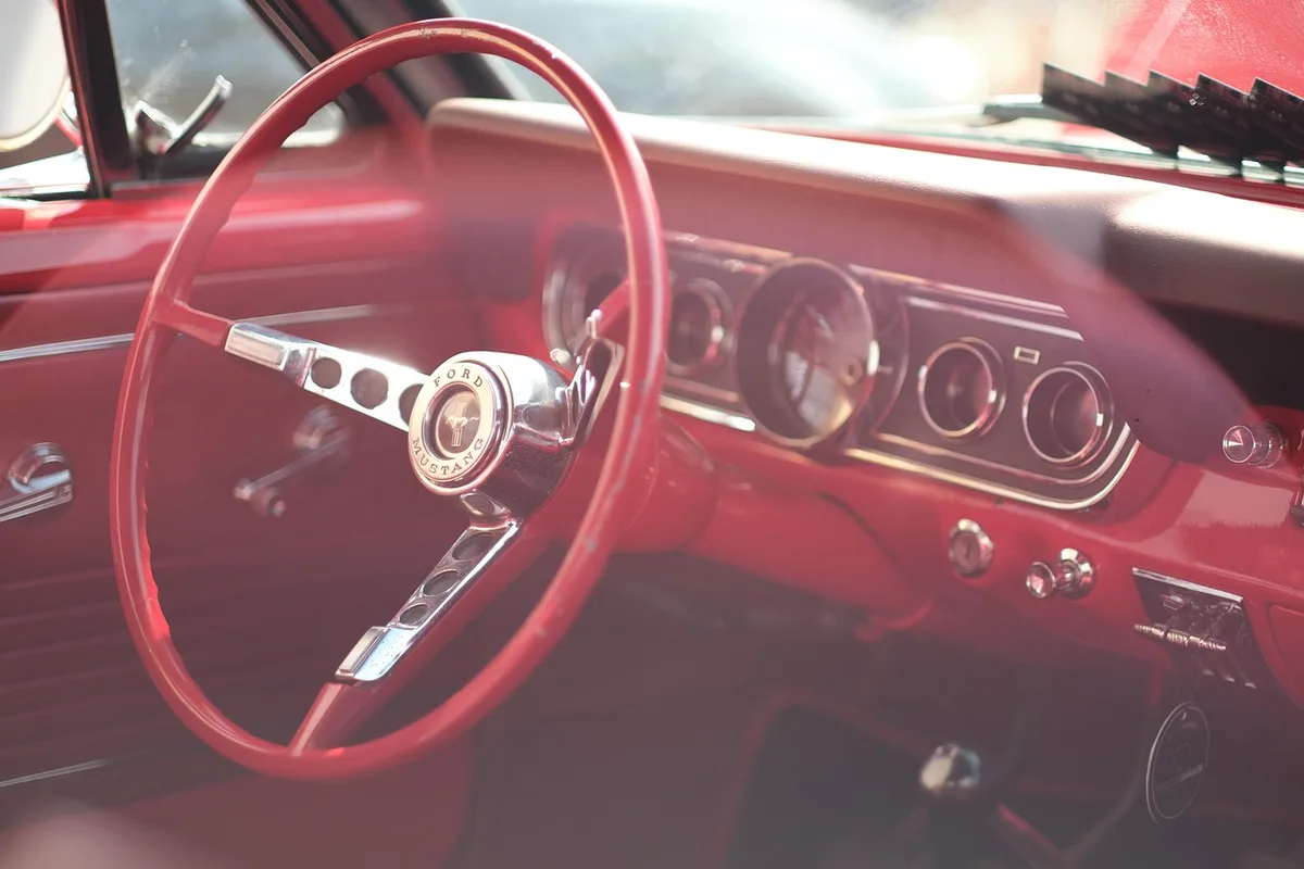 Anonymous hands on a steering wheel with smartphone showing a generic route suggestion, blurred background