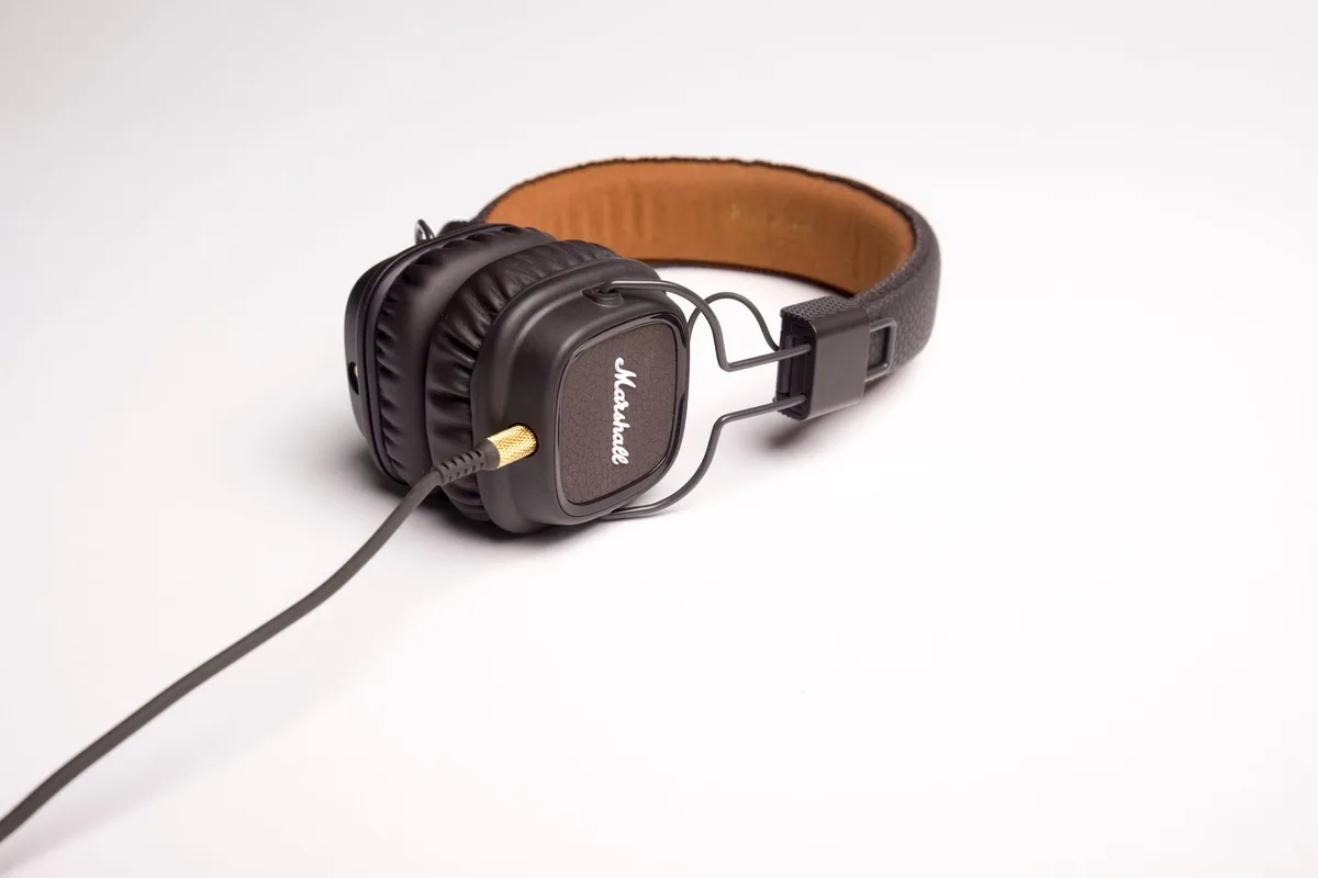 Close shot of an anonymous pair of unbranded over‑ear headphones resting on a plain counter next to an unfolded price label showing a reduced figure; soft shop lighting
