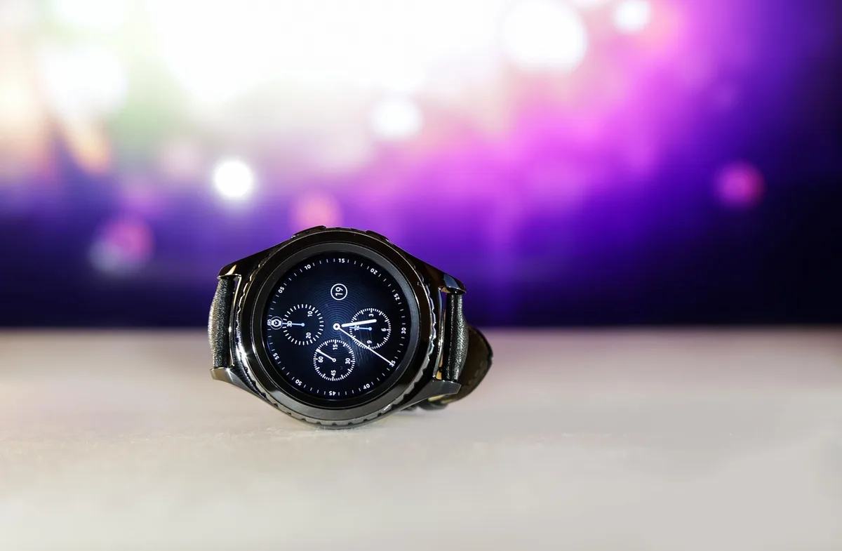 Close-up of an unbranded sport smartwatch with a textured, rugged strap laid on snowy ski equipment; no logos, no people
