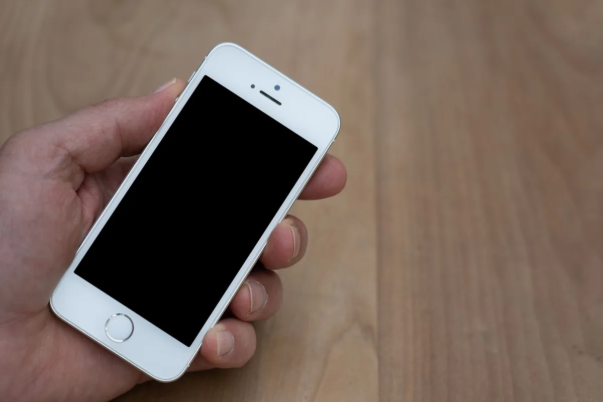 An empty smartphone on a wooden table displaying a generic settings screen blurred, a small update progress bar visible, no brand or logo