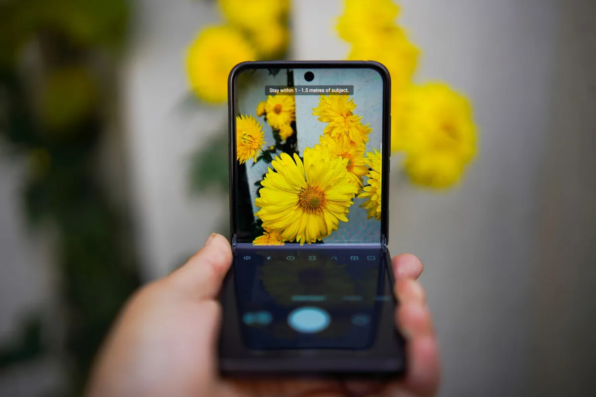 Close-up of an anonymous pair of hands interacting with an unbranded folding smartphone on a display table