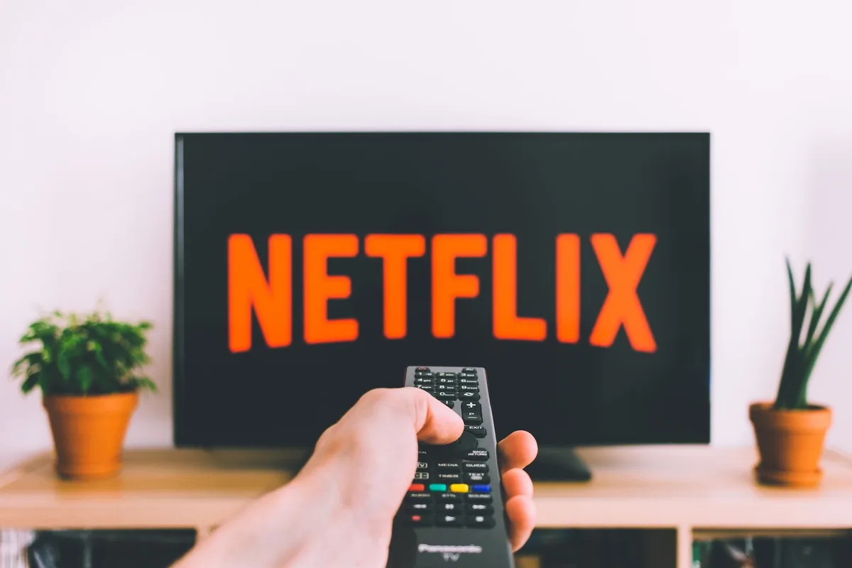 Empty living room TV with an anonymous remote on a coffee table, home-screen icons visible on TV blurred