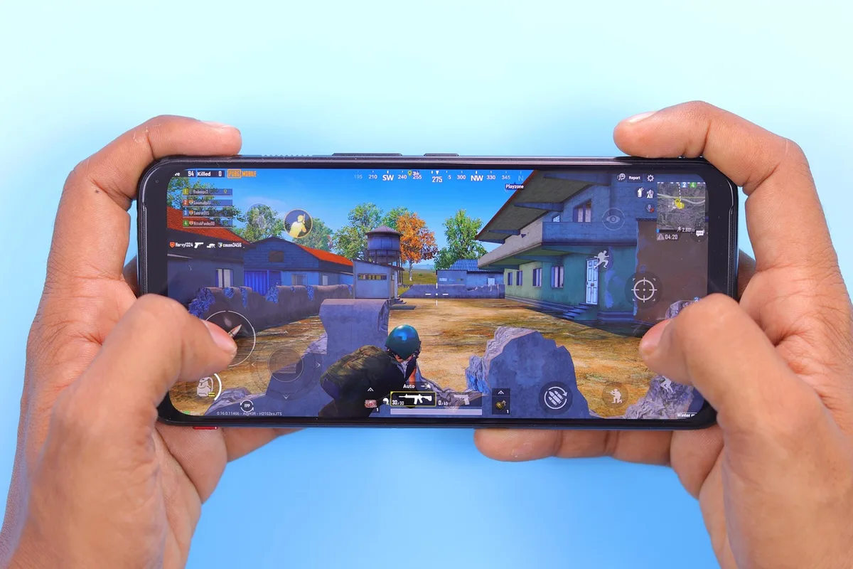 Empty wide shot of an anonymous mobile gaming setup on a table, an unbranded tablet showing a colorful space landscape, a pair of anonymous hands just out of frame