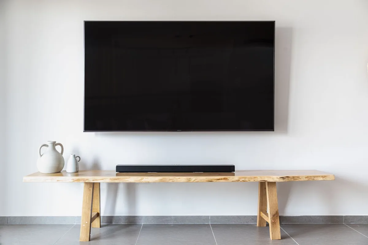Empty TV set on a living-room shelf with a glowing, unbranded horror channel logo on screen, dim lamps and a carved pumpkin nearby