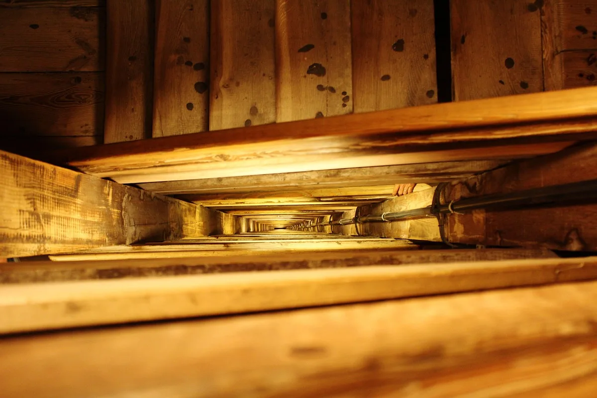 Interior de una escalera industrial de varios niveles con siluetas anónimas